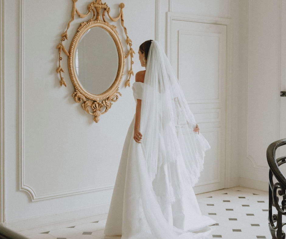 Bride looks in the ornate gold mirror on the landing of the first floor of the Chateau de la Cazine