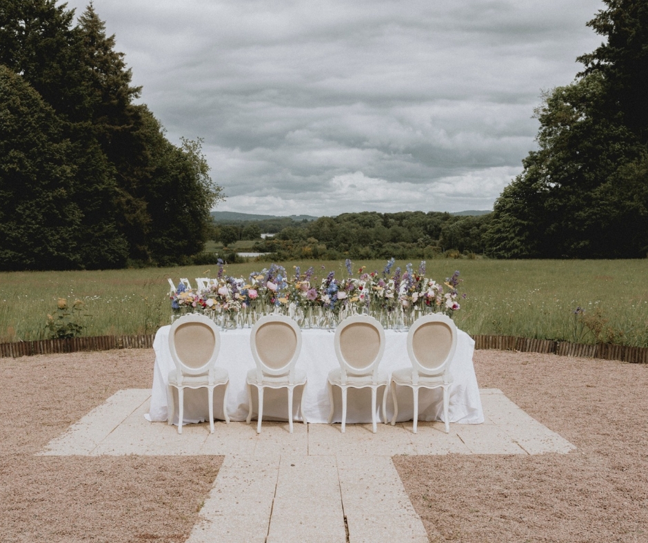 Table of 8 on the terrace of Chateau de la Cazine over looking the lakes and countryside. Pretty white classic Louis Style Chairs.