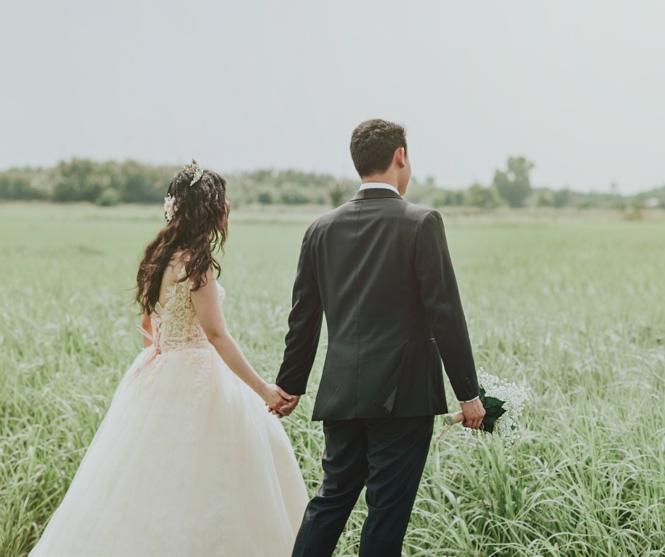 Newlyweds holding hands in the field